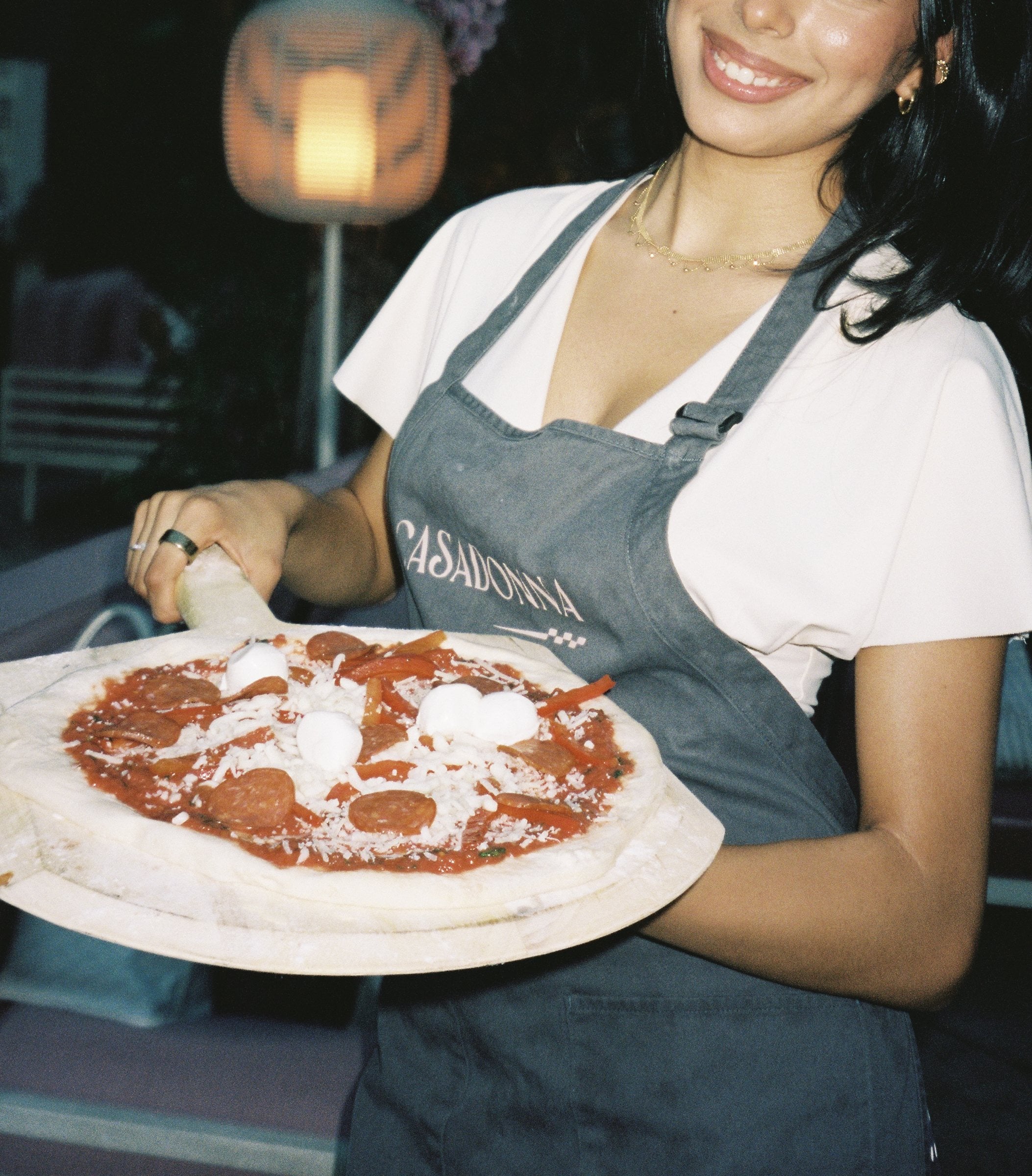 Server holding a finished pizza at Casadonna's pizza-making class