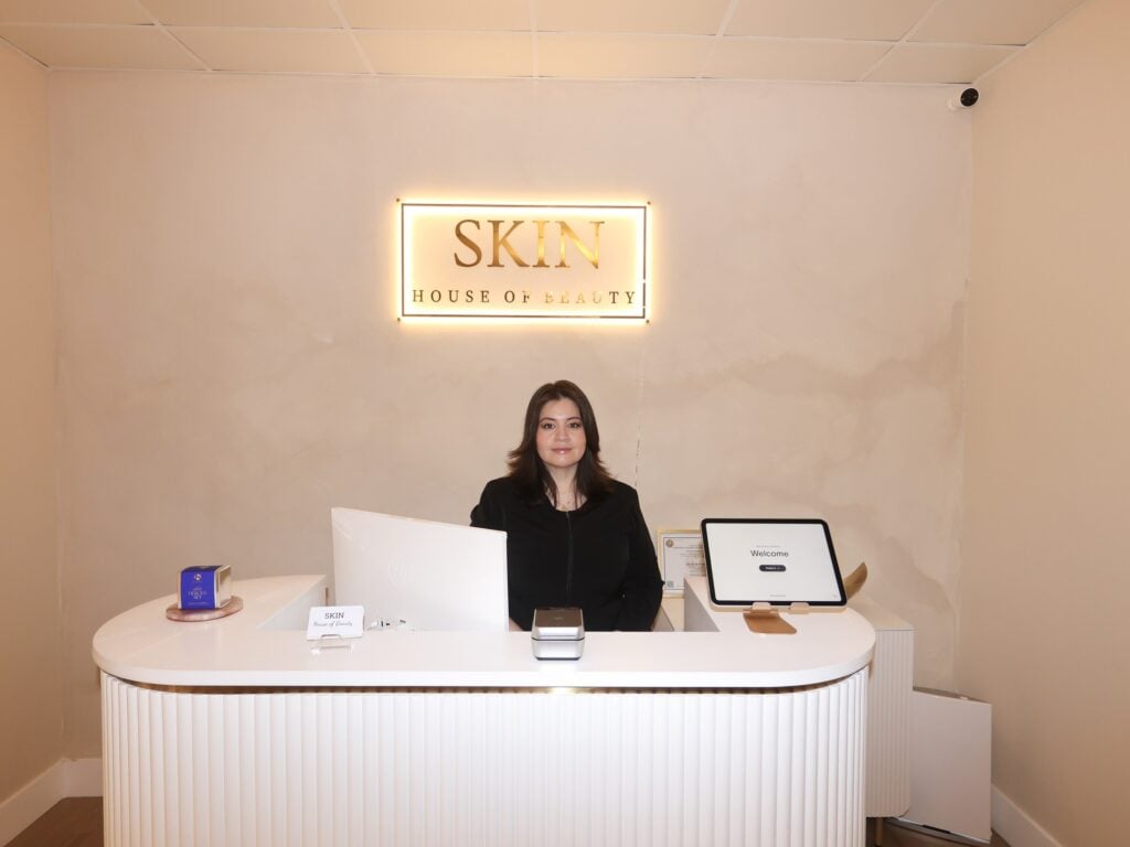 The reception desk at Skin House of Beauty, with the studio's backlit gold sign on the wall
