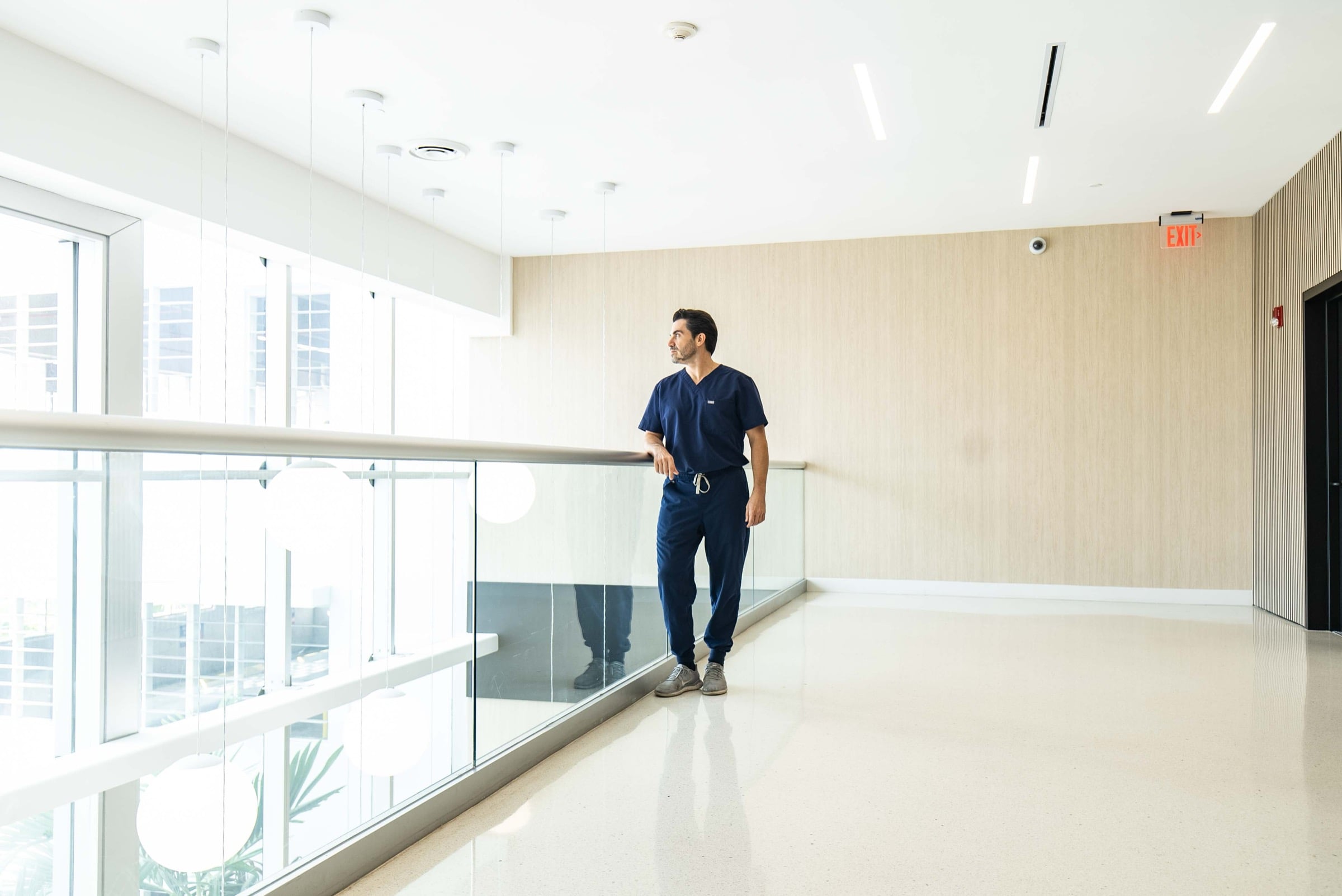 A provider in navy scrubs walking the light-filled corridor at Avabello Aesthetics in Miami Beach