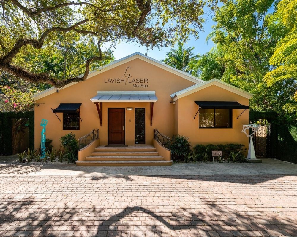 The peach-colored bungalow housing Lavish Laser Medspa in Coconut Grove, framed by oak trees