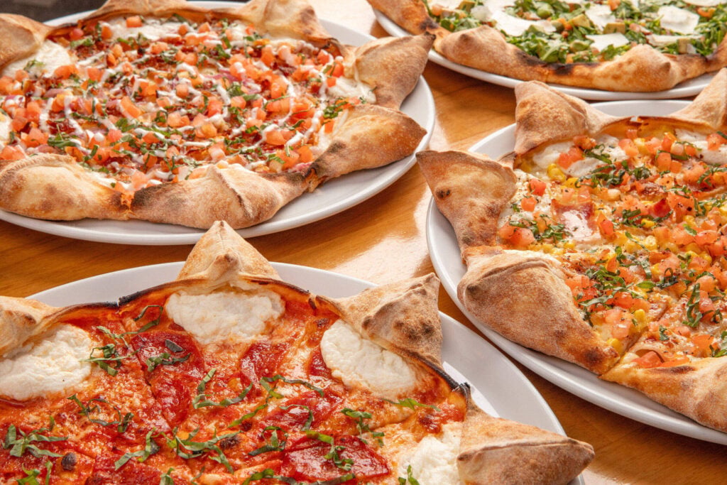 A spread of star-shaped pizzas topped with fresh tomato, basil, and mozzarella at Mister O1 Extraordinary Pizza