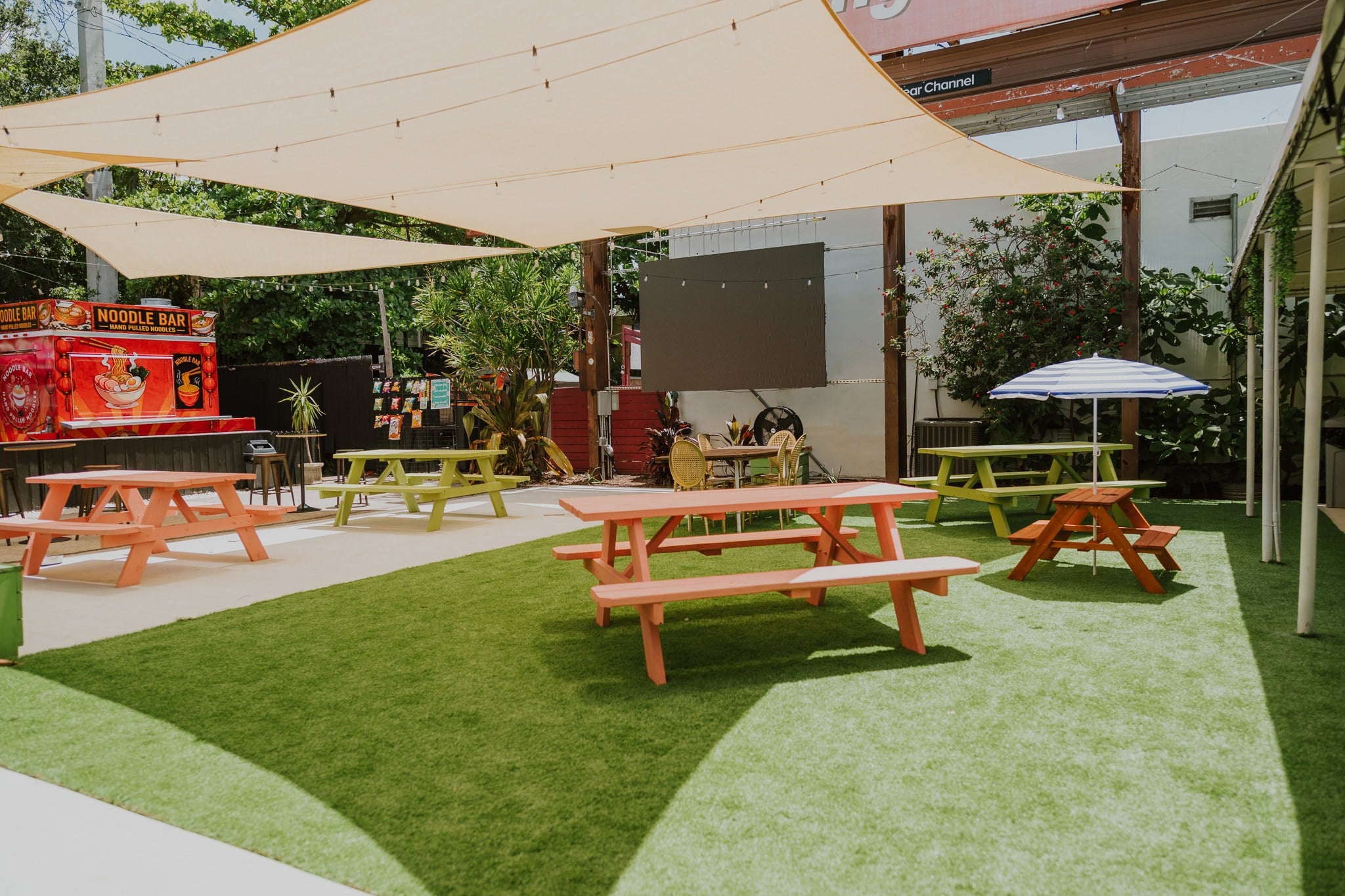 Picnic tables under shade sails in the courtyard at Upper Eastside Hangout