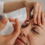 Close-up of a clinician injecting Botox near a patient brow
