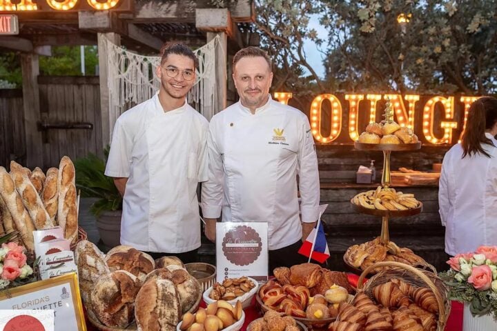 Two bakers behind a display of baguettes, croissants, and pastries at Florida’s Best Baguette and Croissant competition