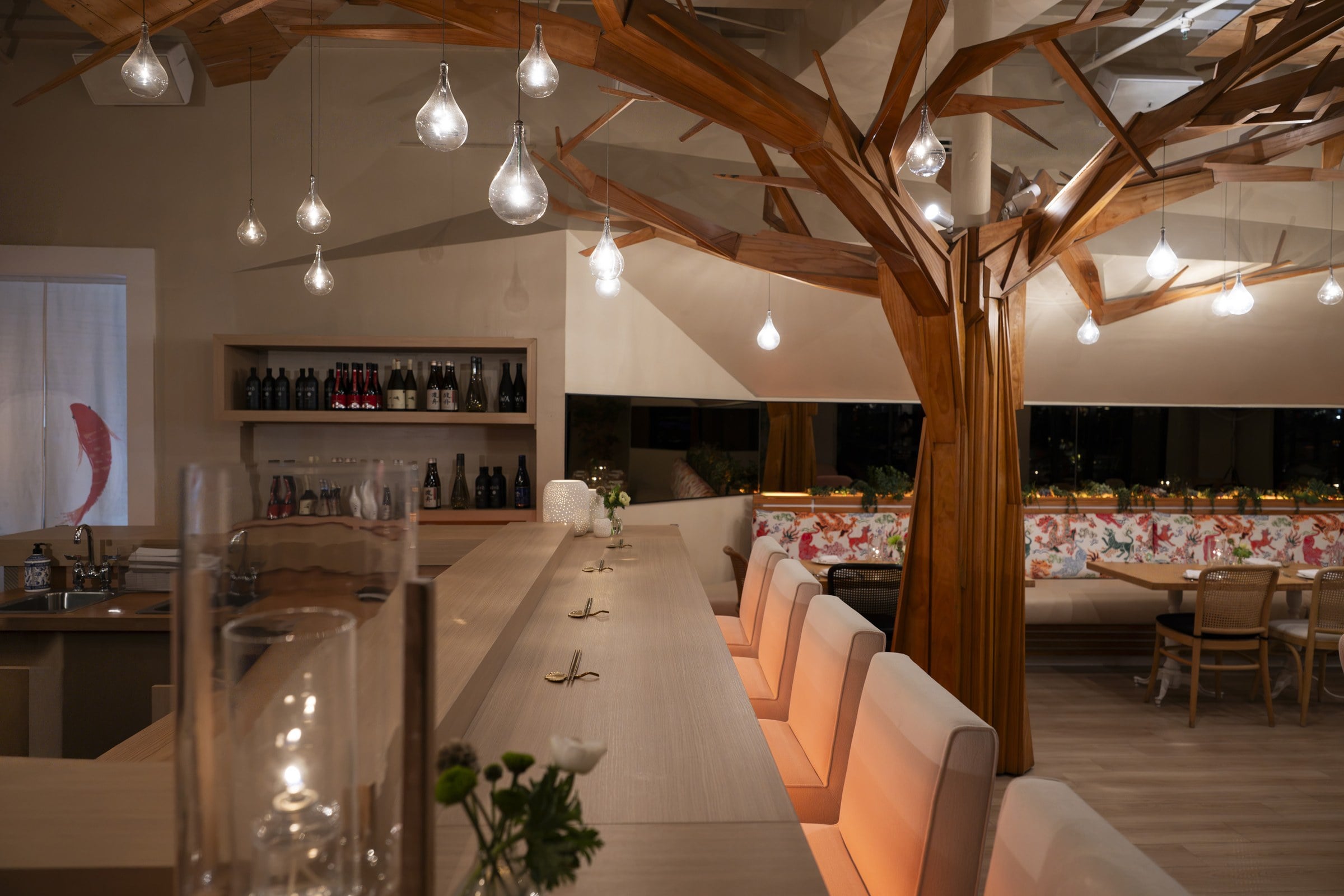 Seaspice dining room with a sculptural wooden tree and omakase counter on the Miami River
