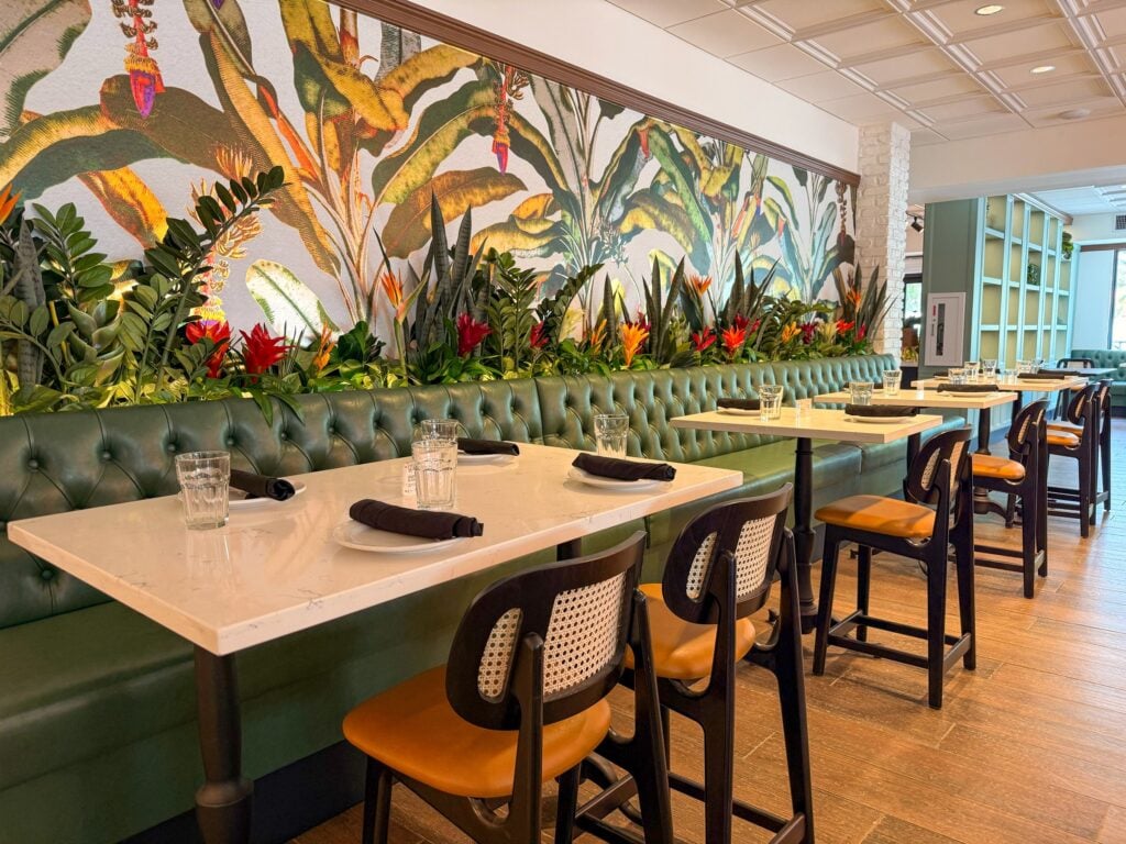 The renovated dining room at Havana Harry’s in Coral Gables, with green leather booths and a tropical mural
